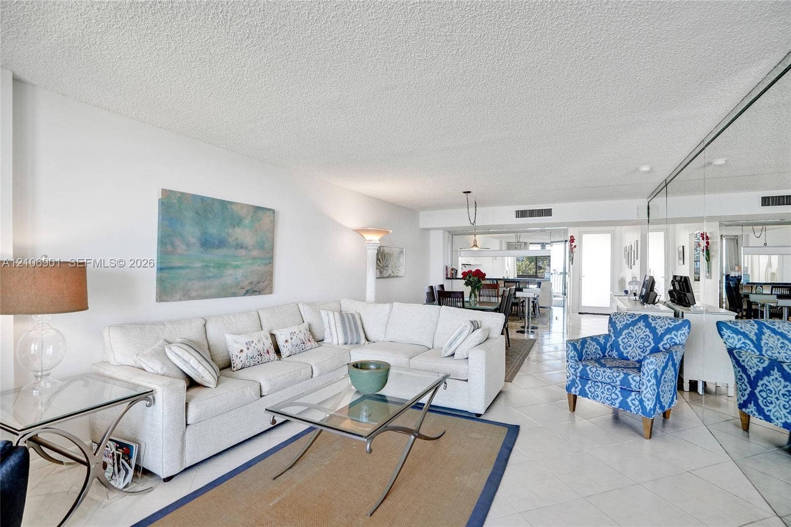 510 N Ocean Boulevard, #308, Pompano Beach, FL 33062 Open-concept living space featuring large-format ceramic tile flooring, full-wall mirrored accent, and textured ceiling finish