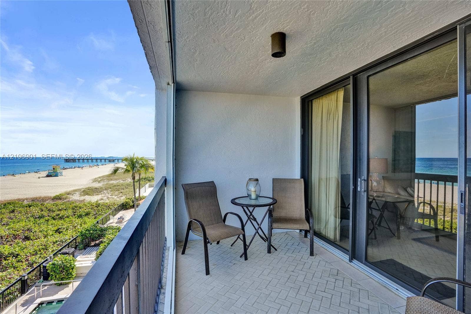 510 N Ocean Boulevard, #308, Pompano Beach, FL 33062 Covered balcony featuring herringbone-pattern tile flooring, dark metal railing, and direct access through large sliding glass doors
