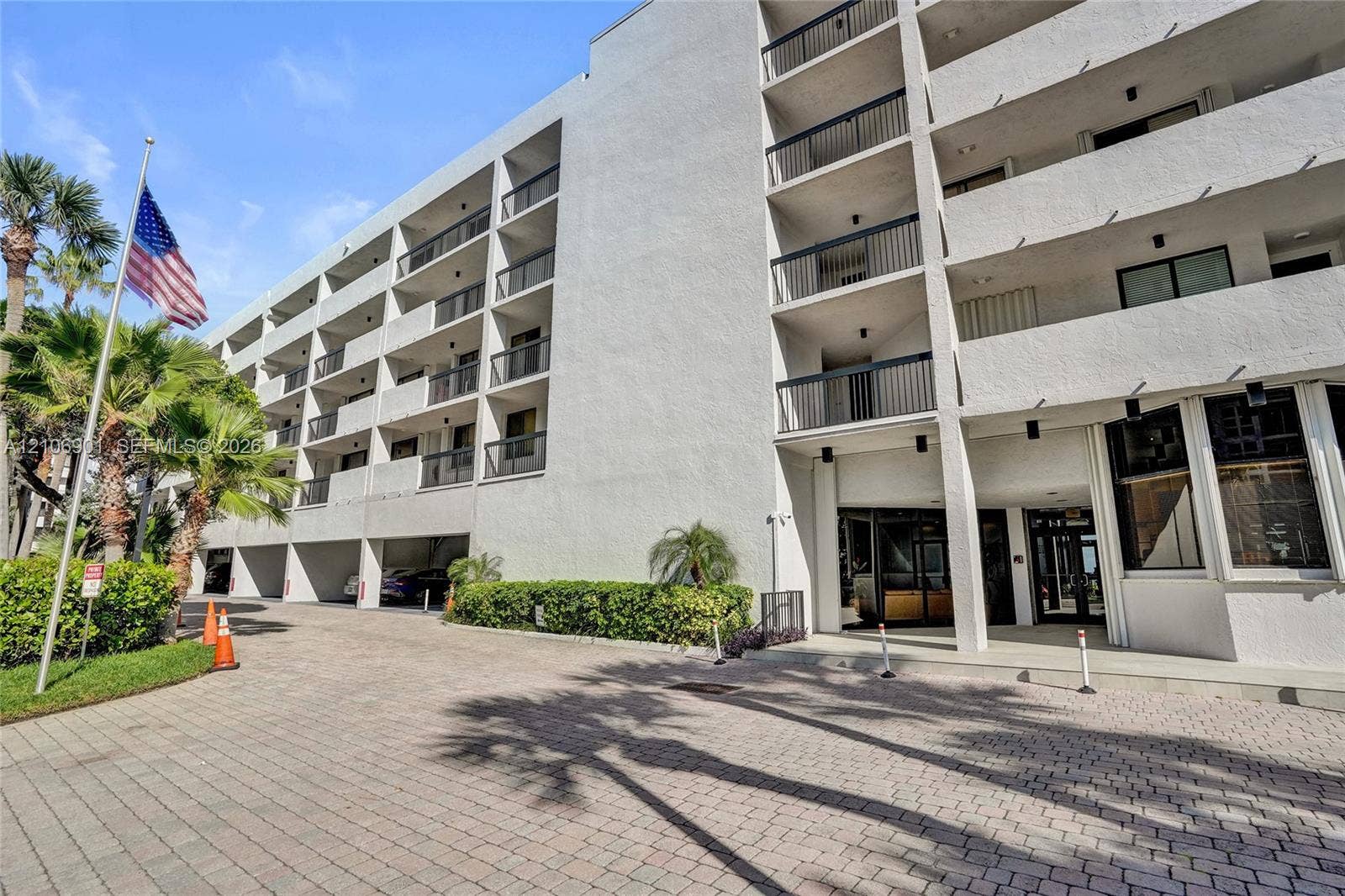 510 N Ocean Boulevard, #308, Pompano Beach, FL 33062 Multi-story concrete exterior featuring private balconies with black metal railings, ground-level covered parking, and paver stone driveway
