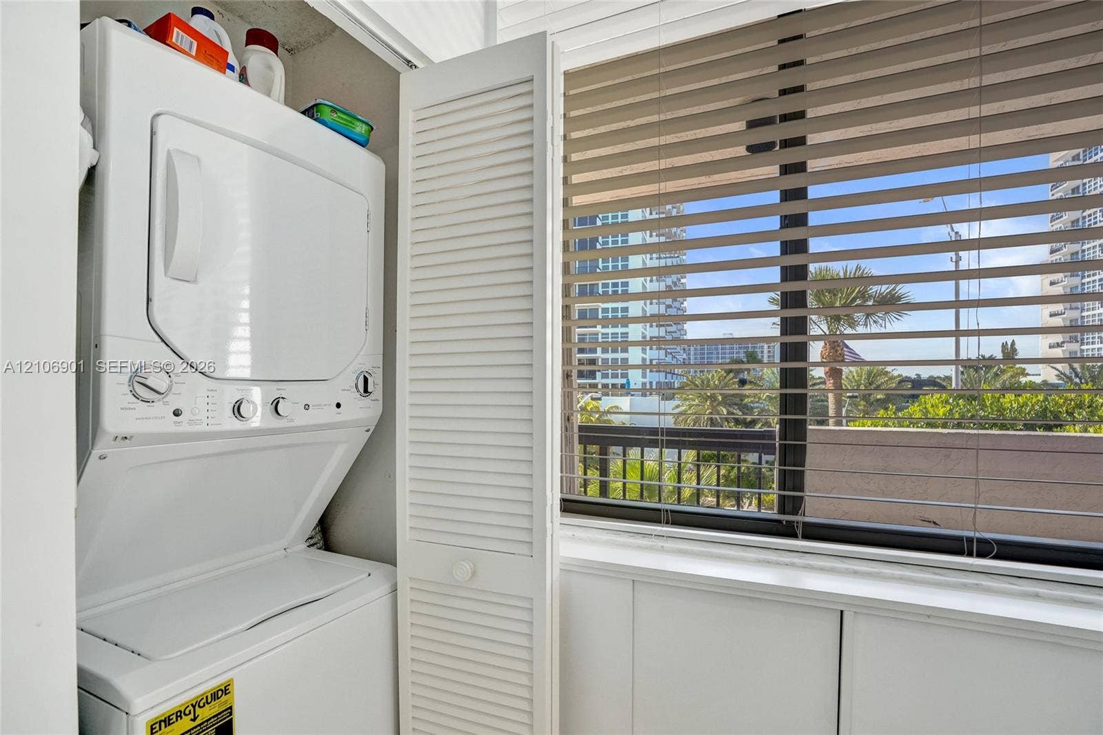 510 N Ocean Boulevard, #308, Pompano Beach, FL 33062 Stacked laundry unit featuring louvered bi-fold doors and large window with horizontal blinds