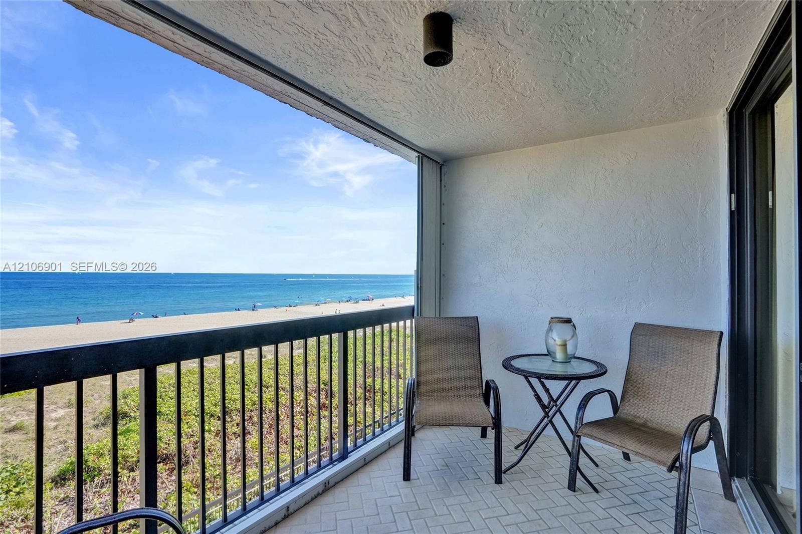 510 N Ocean Boulevard, #308, Pompano Beach, FL 33062 Covered balcony featuring herringbone-patterned tile flooring, black metal railing, and direct water and beach frontage
