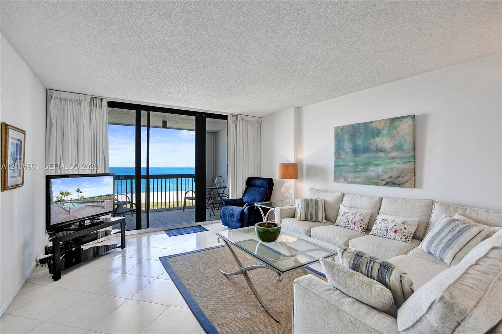 510 N Ocean Boulevard, #308, Pompano Beach, FL 33062 Living area featuring ceramic tile flooring, floor-to-ceiling glass sliding doors, and a covered balcony with a metal railing