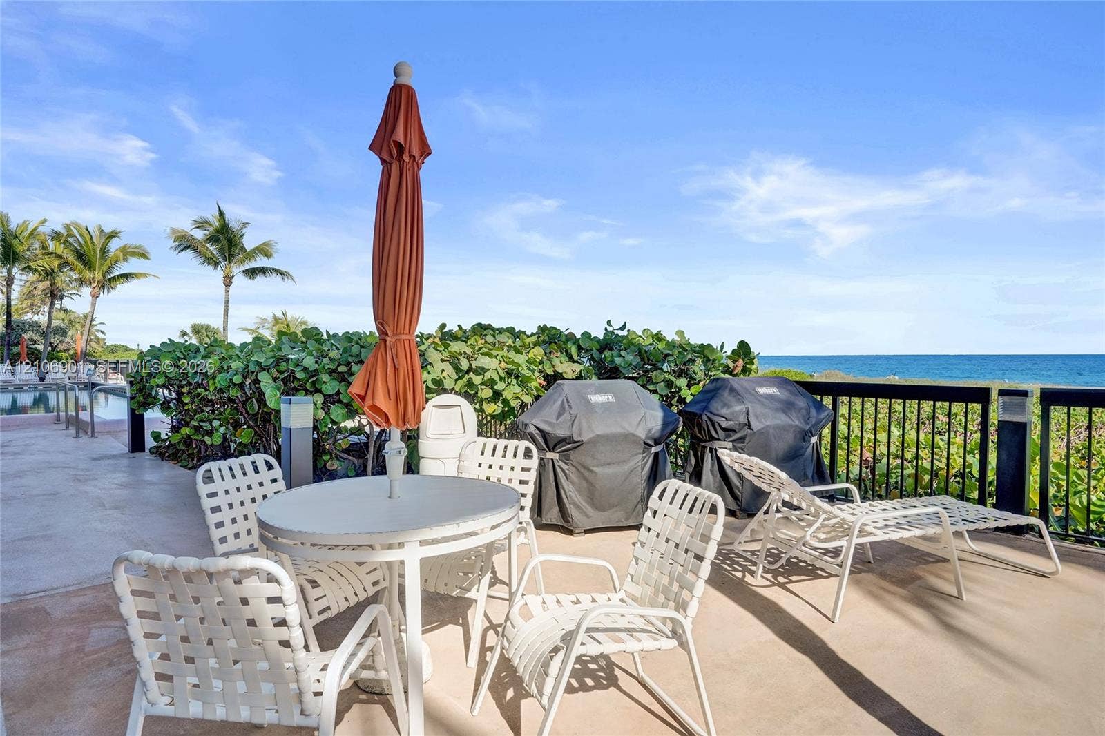 510 N Ocean Boulevard, #308, Pompano Beach, FL 33062 Concrete terrace featuring a black metal perimeter railing, ocean backdrop, and integrated landscape shrubbery