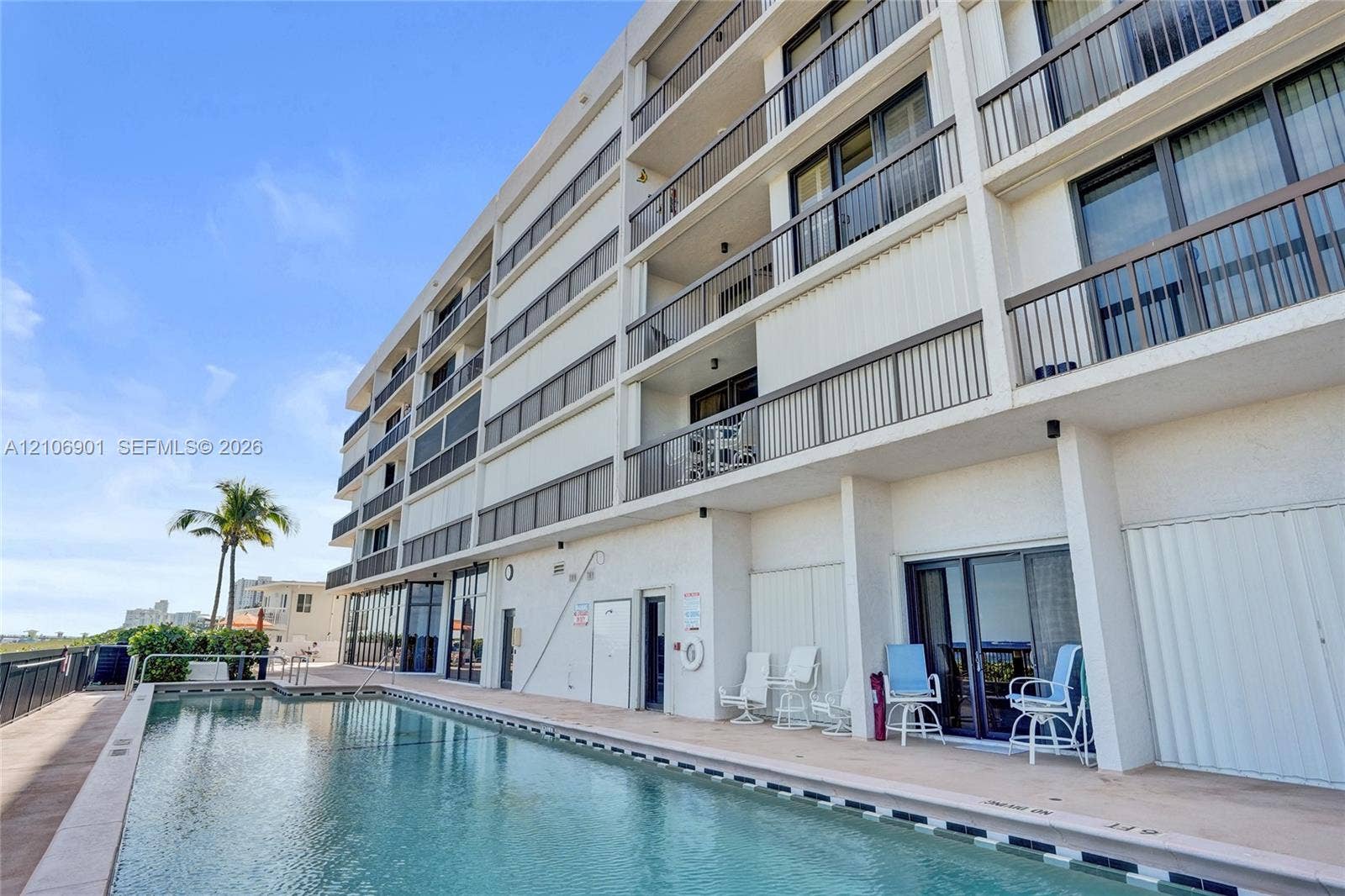 510 N Ocean Boulevard, #308, Pompano Beach, FL 33062 Multi-story building exterior featuring private balconies with metal railings, sliding glass doors, and an outdoor swimming pool with concrete decking