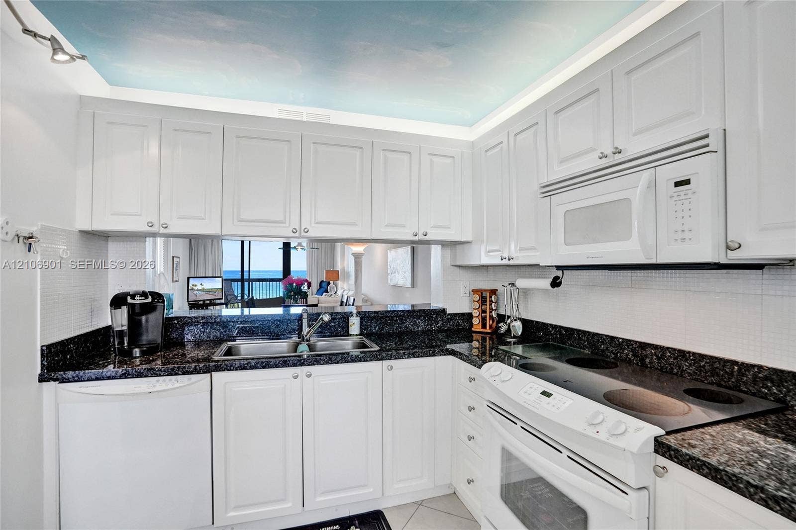 510 N Ocean Boulevard, #308, Pompano Beach, FL 33062 Kitchen featuring white cabinetry, dark stone countertops, built-in microwave, integrated electric cooktop, and tile backsplash