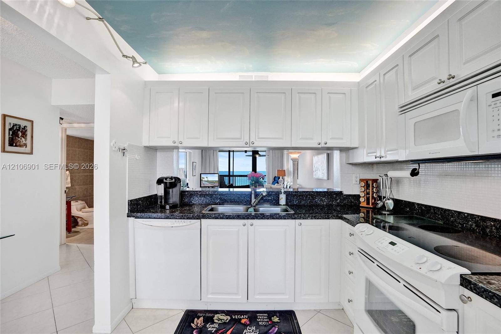 510 N Ocean Boulevard, #308, Pompano Beach, FL 33062 Kitchen featuring white cabinetry, dark stone countertops, built-in white appliances, and a ceiling mural
