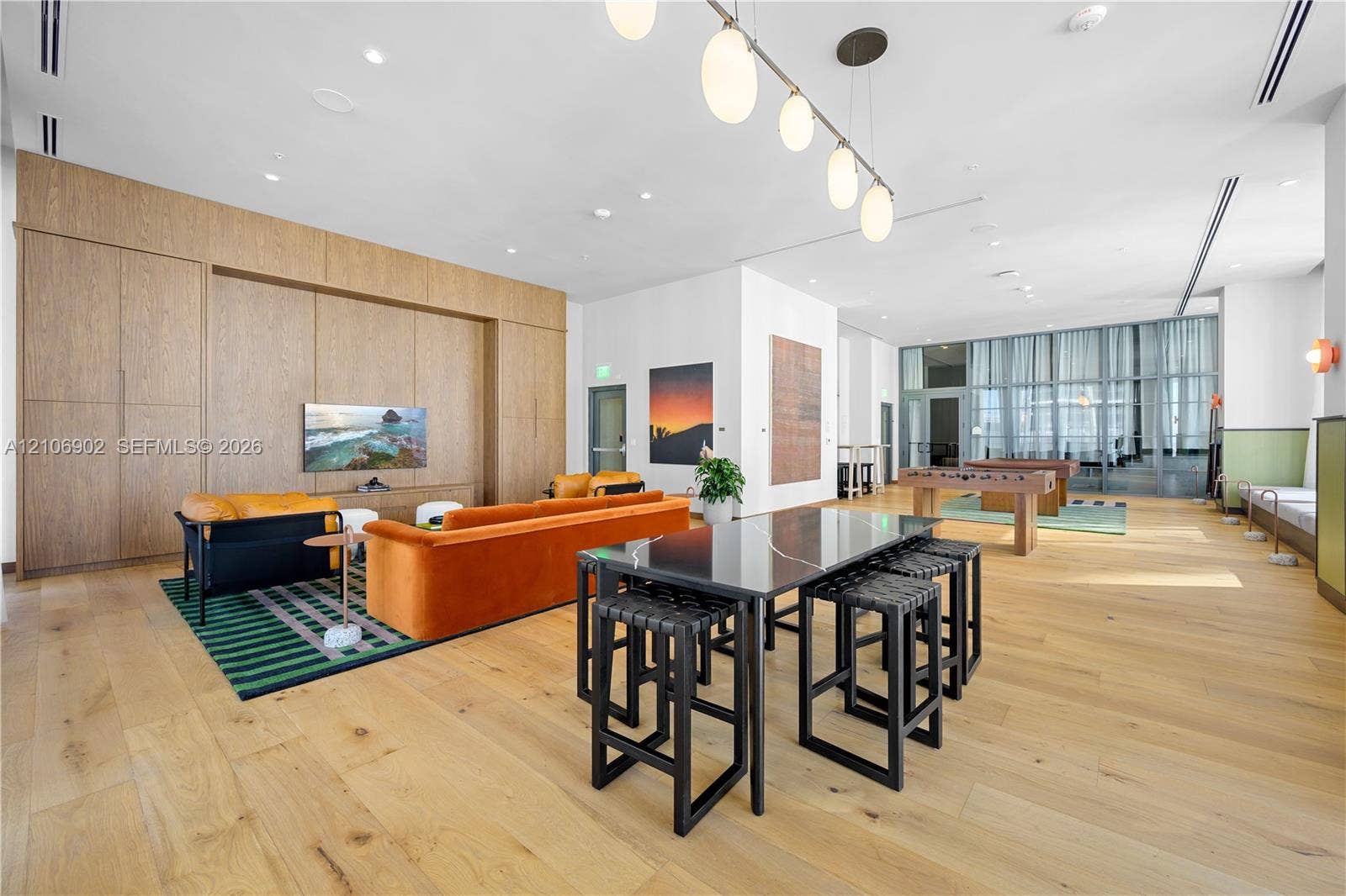 11 NE 6th Street, #1111, Miami, FL 33132 Open-concept interior featuring light wood-finish flooring, extensive built-in wood cabinetry, a polished dark stone surface table, and multi-light linear pendant fixture