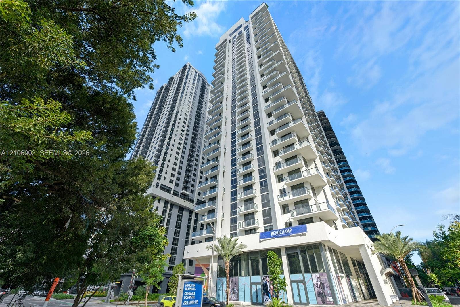 11 NE 6th Street, #1111, Miami, FL 33132 High-rise building exterior featuring a white concrete facade, glass-paneled balconies, and ground-level commercial space