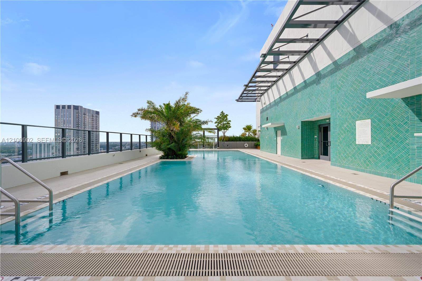 11 NE 6th Street, #1111, Miami, FL 33132 Rooftop swimming pool featuring a tiled accent wall, metal-frame pergola, integrated landscaping, and metal perimeter railing