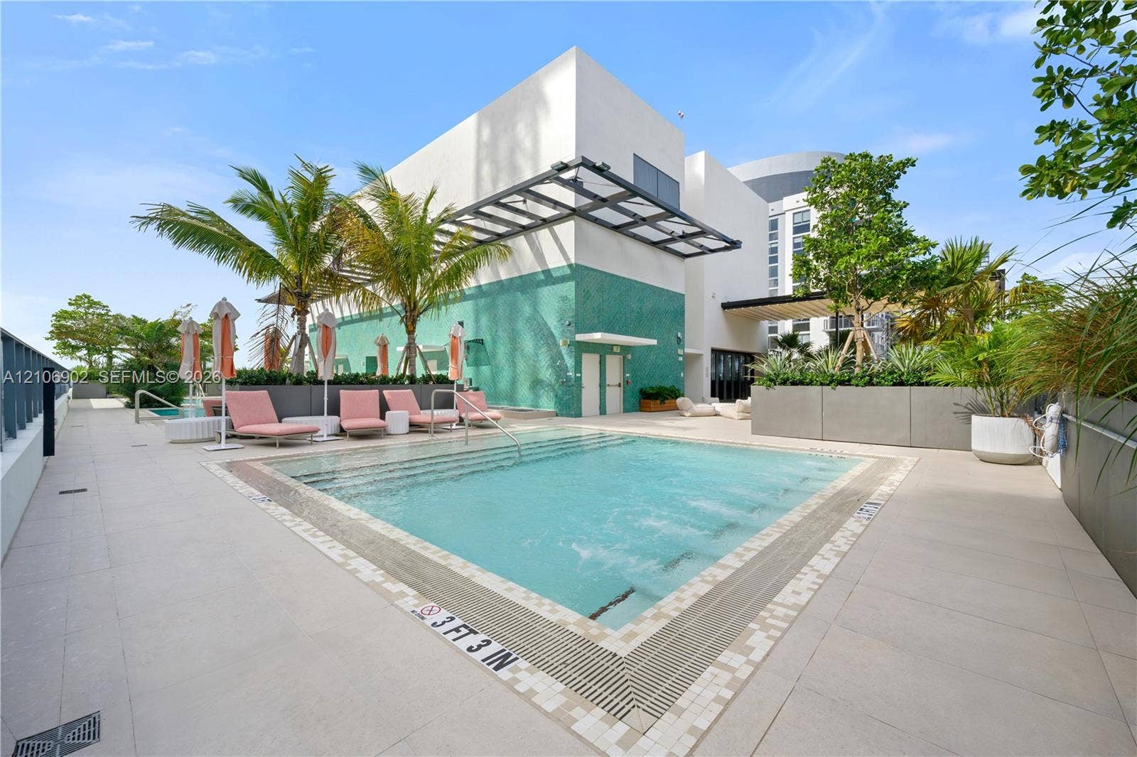 11 NE 6th Street, #1111, Miami, FL 33132 Swimming pool with integrated steps, tile decking, turquoise mosaic exterior wall, and metal overhead architectural canopy