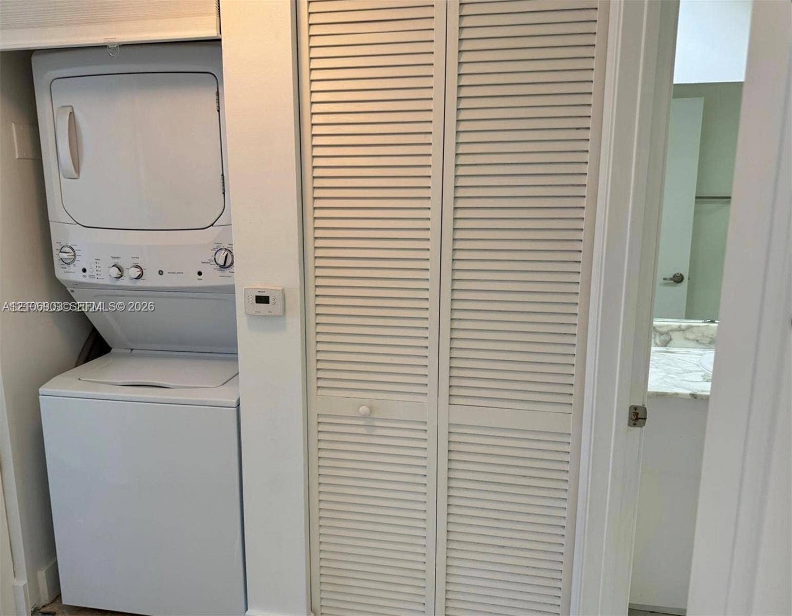Stacked washer and dryer unit with louvered bi-fold closet doors