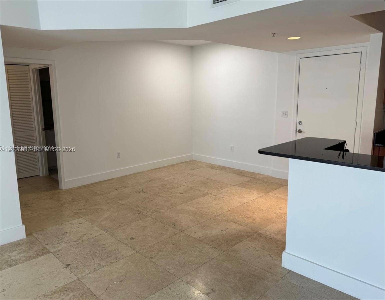 Open interior space featuring high vaulted ceilings, large-format tile flooring, and a breakfast bar with a solid surface countertop