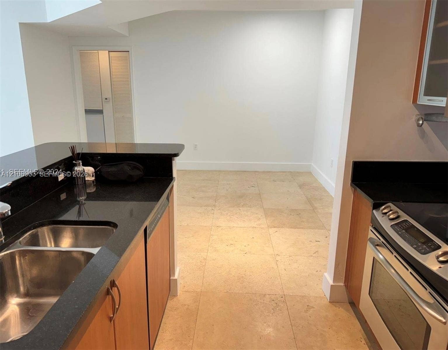 Kitchen featuring stone countertops, flat-panel cabinetry, stainless steel range, double-basin undermount sink, and tile flooring