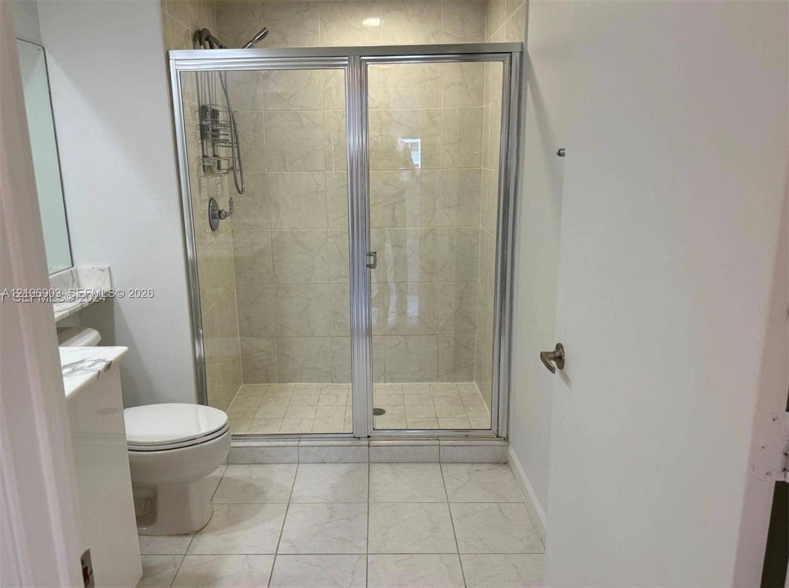 Walk-in shower with a glass enclosure, tiled wall surround, vanity with a stone countertop, and large-format tile flooring