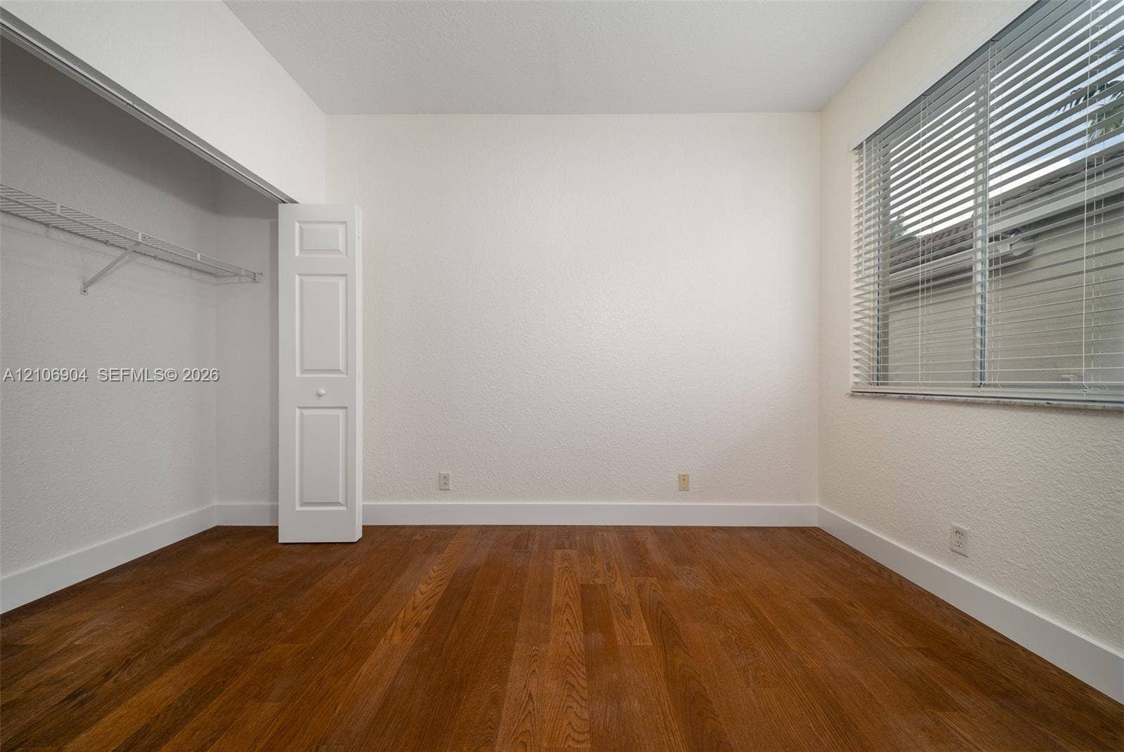 297 Conservation Drive, Weston, FL 33327 Room featuring wood-finish flooring, a window with horizontal blinds, and a built-in closet with a panel door