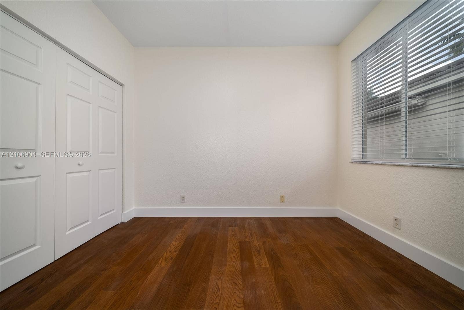 297 Conservation Drive, Weston, FL 33327 Room featuring wood-finish flooring, white paneled closet doors, and a window with horizontal blinds