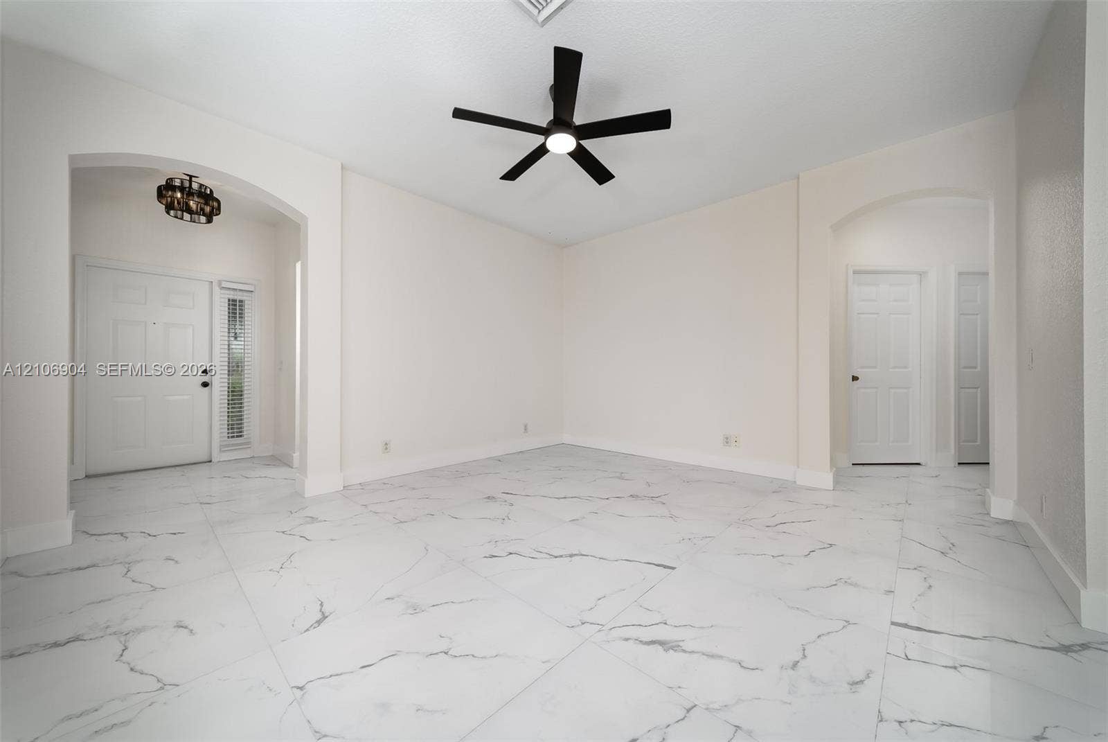 297 Conservation Drive, Weston, FL 33327 Large-format tile flooring with a neutral-toned veined pattern, recessed archways, matte black ceiling fan with integrated lighting, and multi-panel entry door featuring a vertical glass sidelight