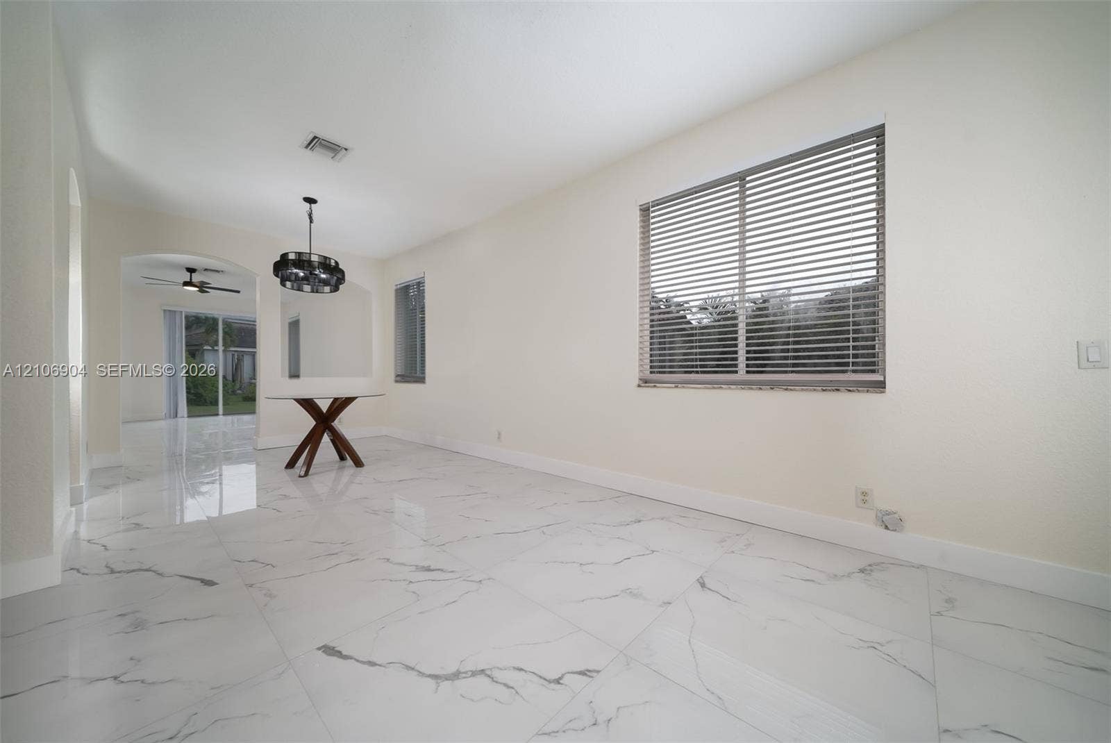 297 Conservation Drive, Weston, FL 33327 Large-format white tile flooring with grey veining, arched entryway, multi-light metal chandelier, and horizontal window blinds
