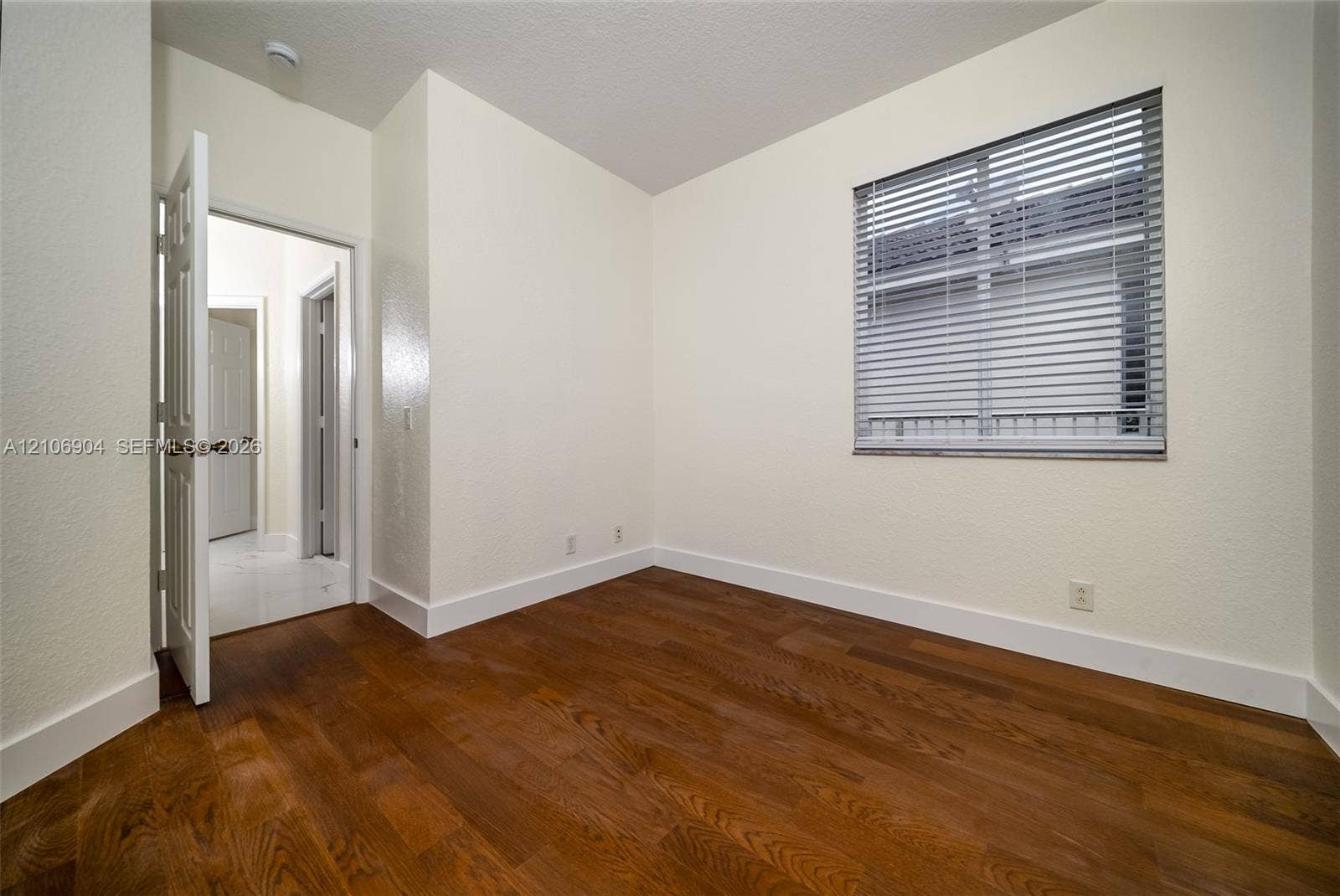 297 Conservation Drive, Weston, FL 33327 Room featuring wood-finish flooring, neutral wall paint, and a window with horizontal blinds