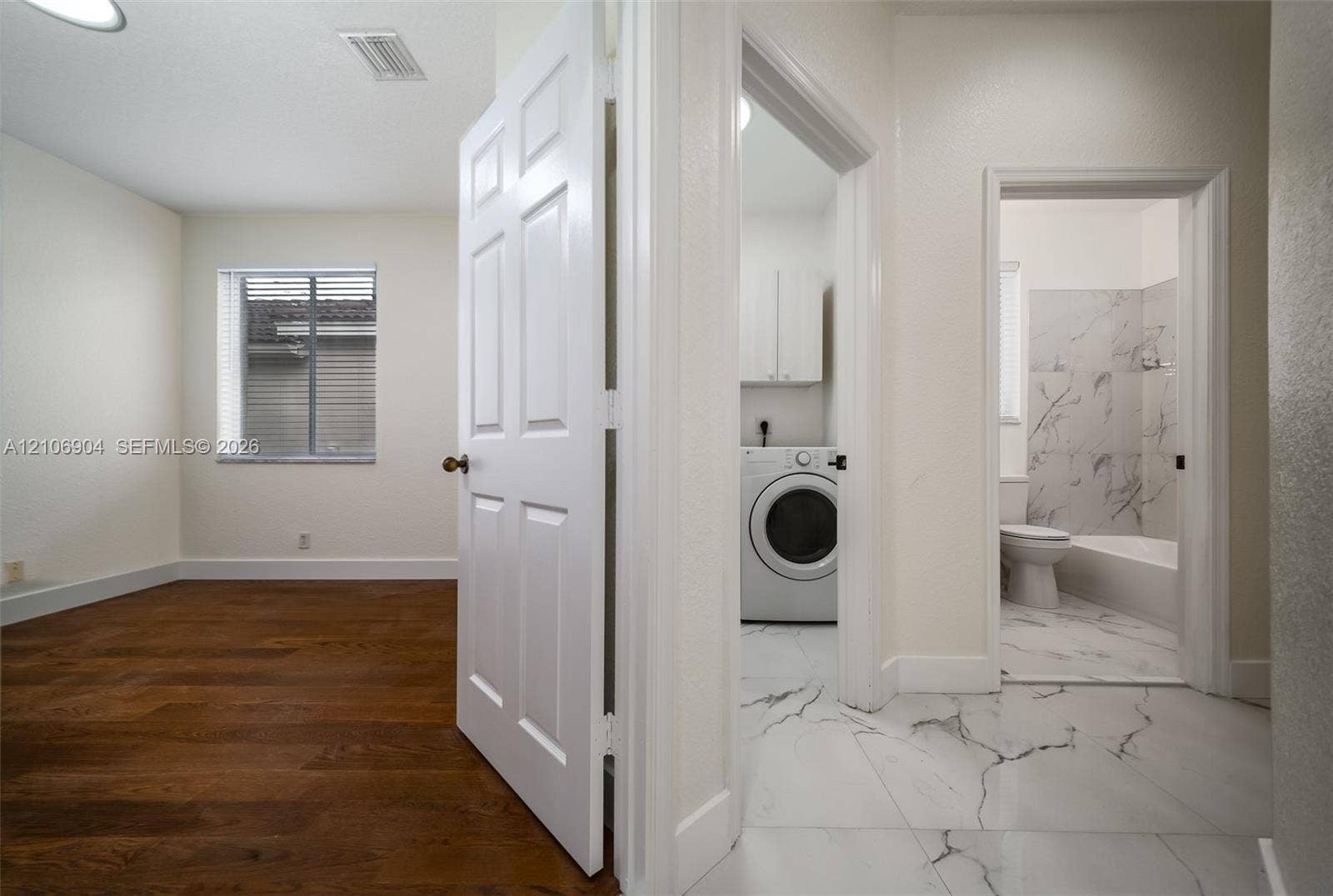 297 Conservation Drive, Weston, FL 33327 Interior featuring wood-finish flooring, large-format tile flooring, six-panel doors, and a tiled shower surround