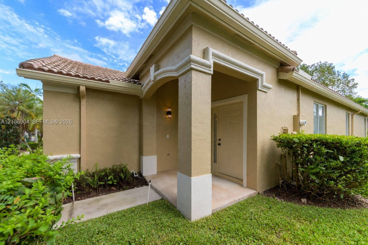 297 Conservation Drive, Weston, FL 33327 Stucco exterior featuring a covered entryway, arched architectural detailing, a tiled roof, and a concrete walkway