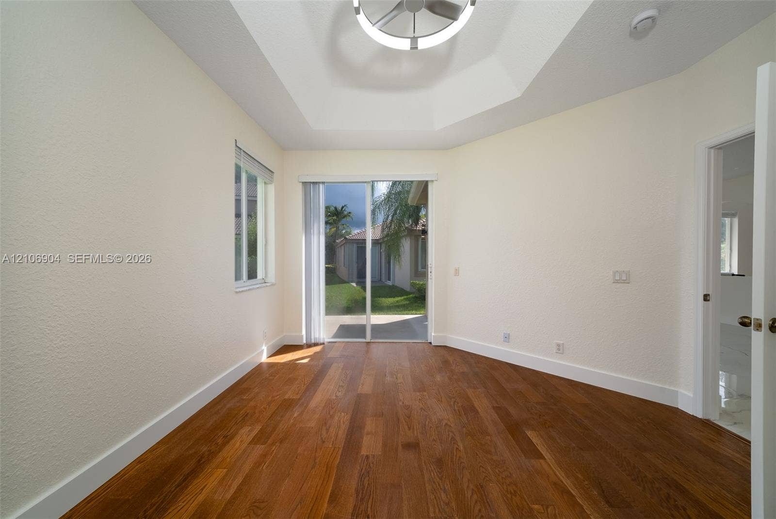 297 Conservation Drive, Weston, FL 33327 Room featuring wood-finish flooring, tray ceiling with circular LED fixture, and sliding glass door with exterior access