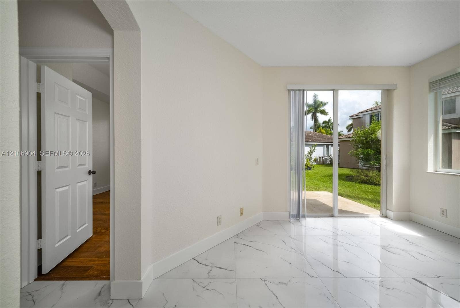 297 Conservation Drive, Weston, FL 33327 Interior featuring large-format white stone-finish flooring with dark veining, sliding glass patio doors, and a six-panel interior door