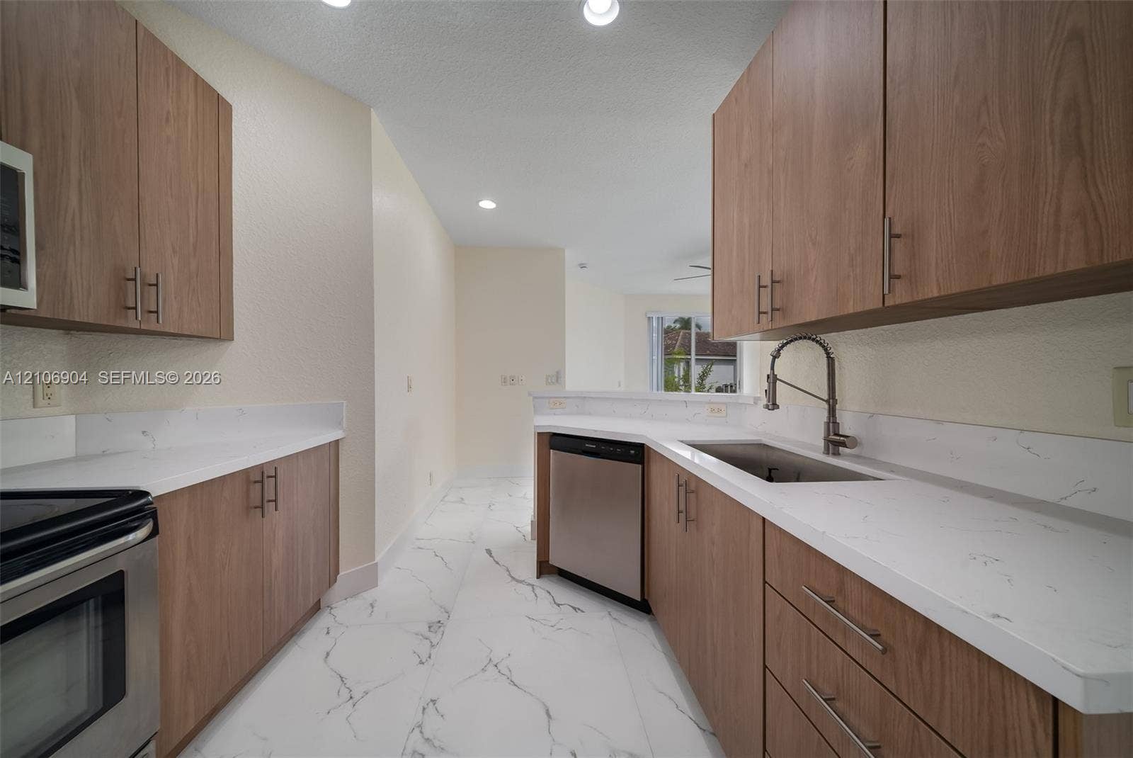 297 Conservation Drive, Weston, FL 33327 Kitchen featuring wood-finish cabinetry, white stone-patterned countertops, stainless steel appliances, and tile flooring with a marble pattern