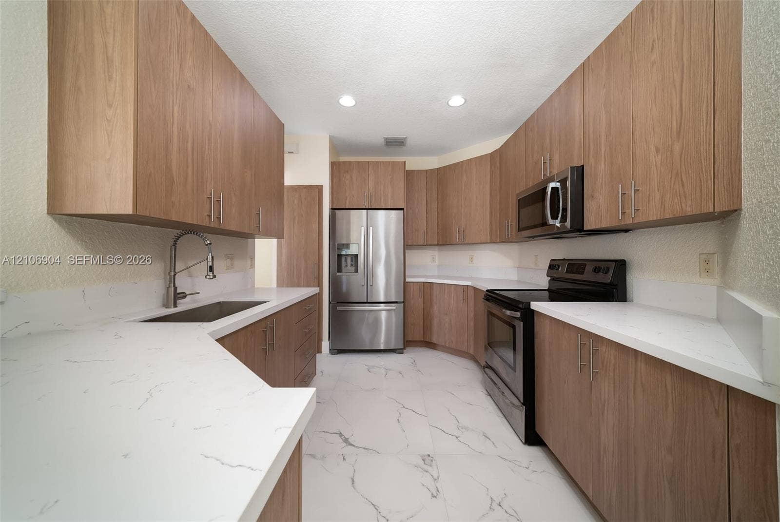 297 Conservation Drive, Weston, FL 33327 Kitchen featuring wood-finish cabinetry, quartz countertops, stainless steel appliances, and large-format tile flooring