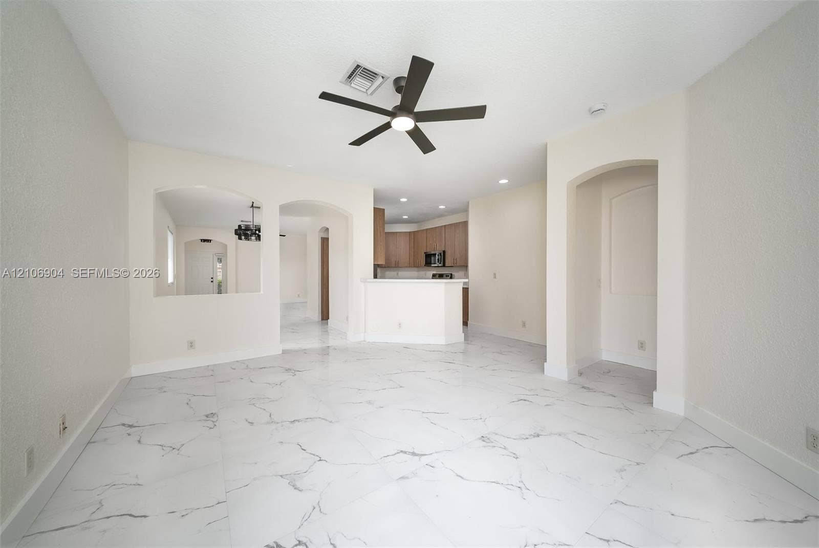 297 Conservation Drive, Weston, FL 33327 Large-format white tile flooring with veining detail, multi-blade ceiling fan with integrated lighting, arched wall openings, and recessed ceiling lighting