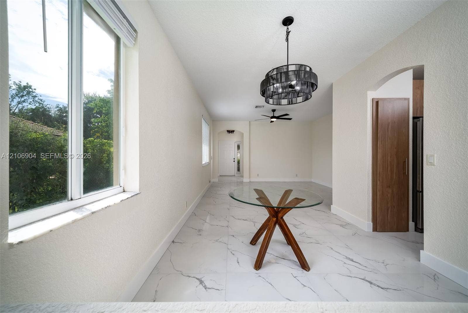 297 Conservation Drive, Weston, FL 33327 Large-format stone-finish tile flooring, decorative multi-tiered drum chandelier, recessed ceiling lighting, arched entryway, and dual-pane windows