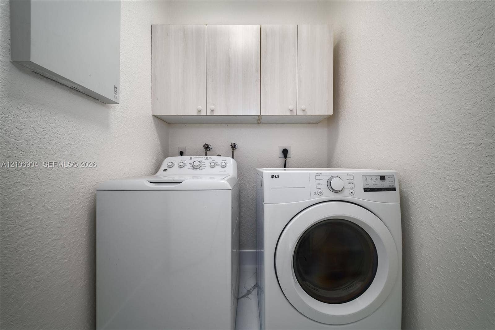 297 Conservation Drive, Weston, FL 33327 Laundry area featuring light-finish wood cabinetry and wall-mounted storage unit