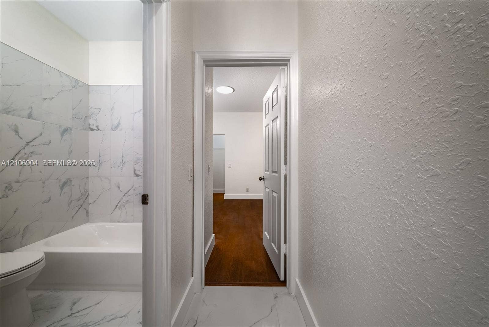 297 Conservation Drive, Weston, FL 33327 Bathroom featuring large-format tile flooring and wall-surround, integrated bathtub, and wood-finish flooring in the additional room