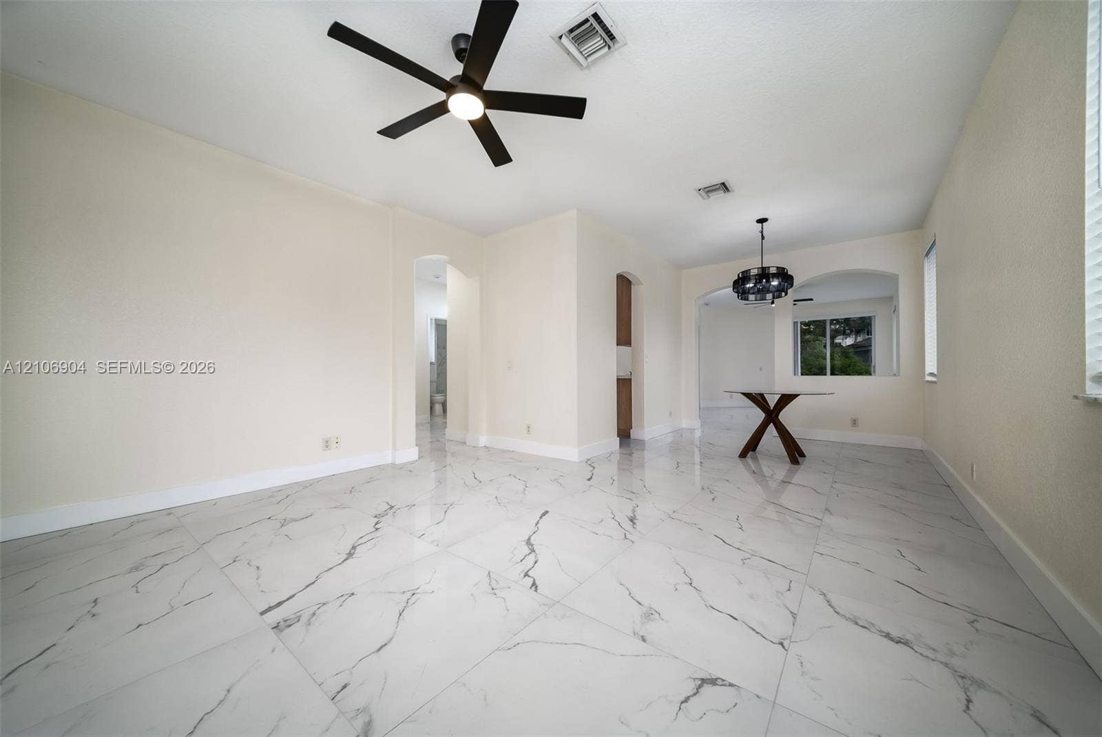 297 Conservation Drive, Weston, FL 33327 Large-format tile flooring with marble-pattern veining, matte black ceiling fan, and decorative chandelier featuring geometric hardware