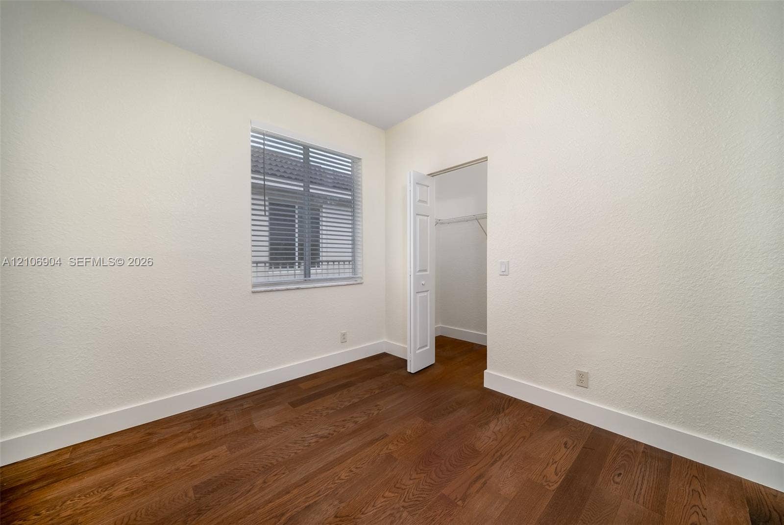 297 Conservation Drive, Weston, FL 33327 Wood-finish flooring, neutral wall tones, window with horizontal blinds, and a closet with a bifold door