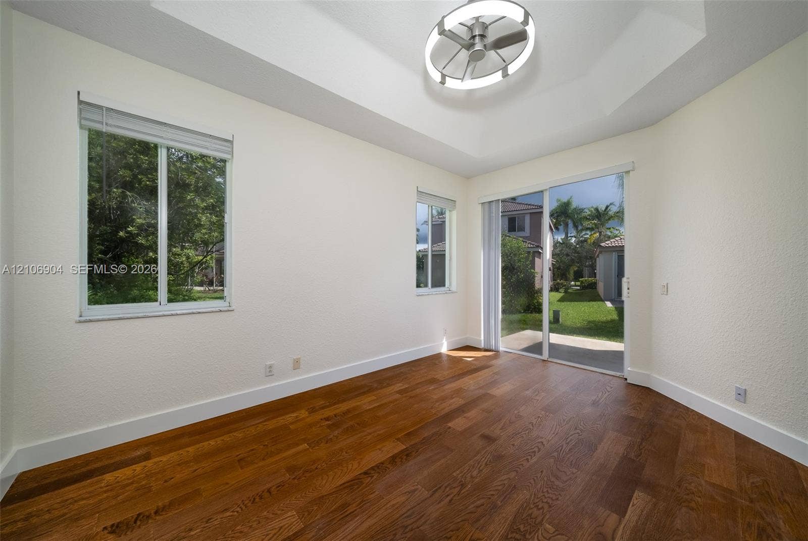 297 Conservation Drive, Weston, FL 33327 Tray ceiling with integrated circular lighting, wood-finish flooring, and sliding glass door access to the exterior