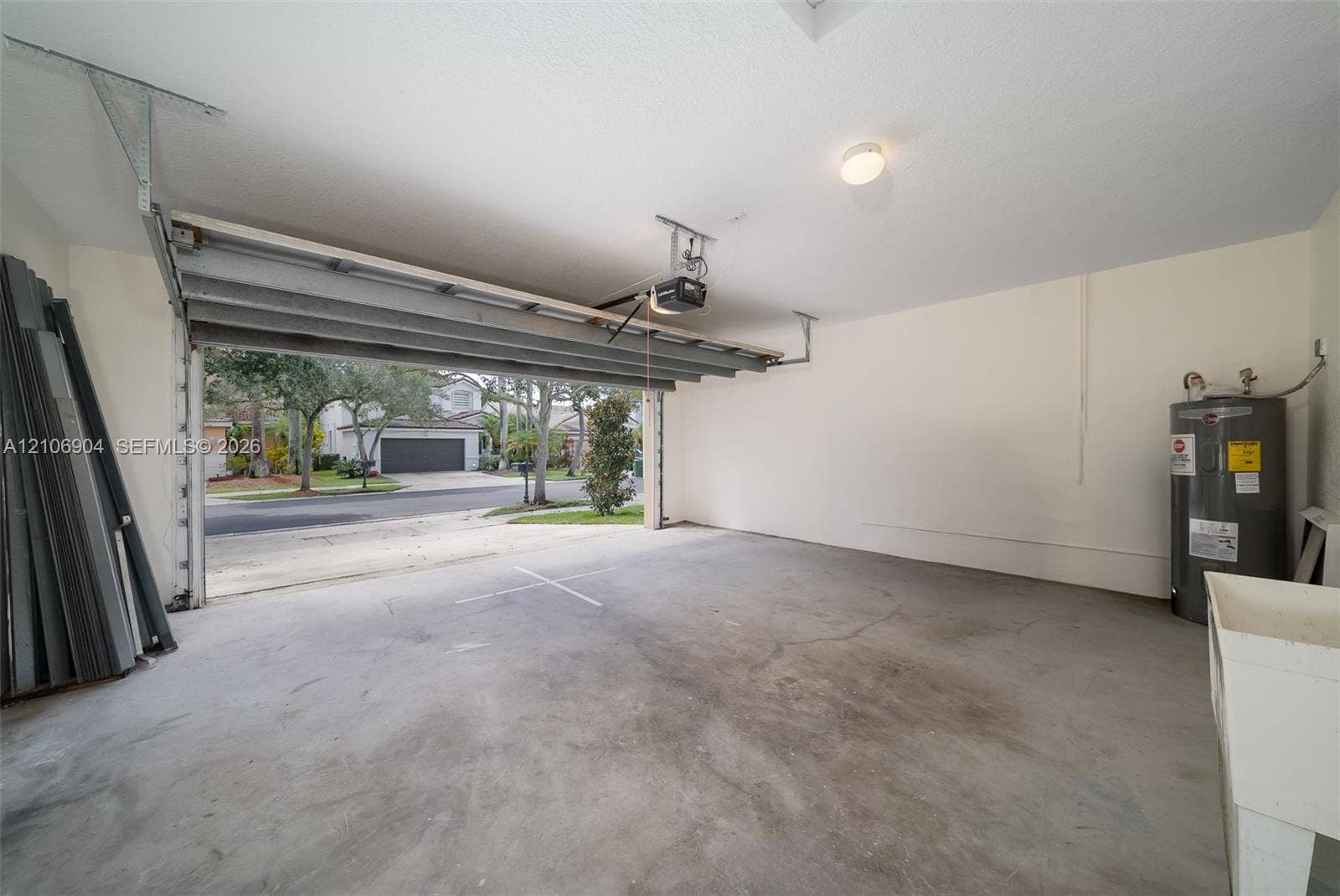 297 Conservation Drive, Weston, FL 33327 Multi-car garage featuring a concrete floor, automated overhead door, ceiling-mounted opener, water heater, and utility basin