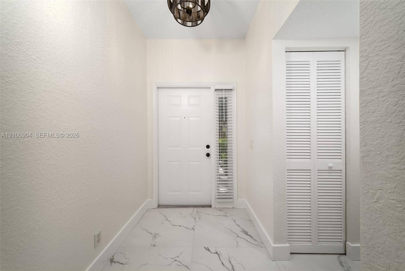 297 Conservation Drive, Weston, FL 33327 Entryway featuring large-format veined tile flooring, a multi-panel door with a sidelight, a louvered-panel closet door, and a circular drum pendant light fixture