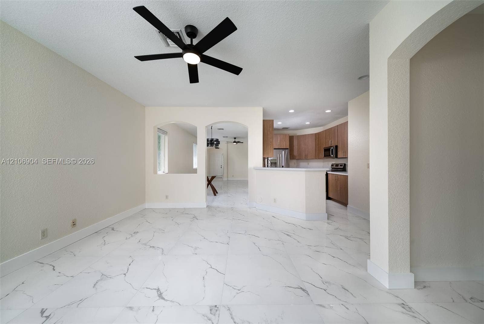 297 Conservation Drive, Weston, FL 33327 Large-format stone-look tile flooring featuring marbled veining, arched wall openings, neutral wall finish, and modern matte black ceiling fan