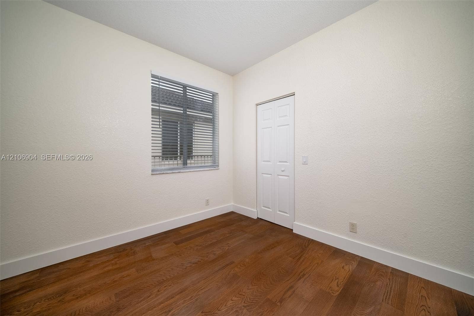 297 Conservation Drive, Weston, FL 33327 Room featuring wood-finish flooring, a six-panel closet door, and a multi-pane window