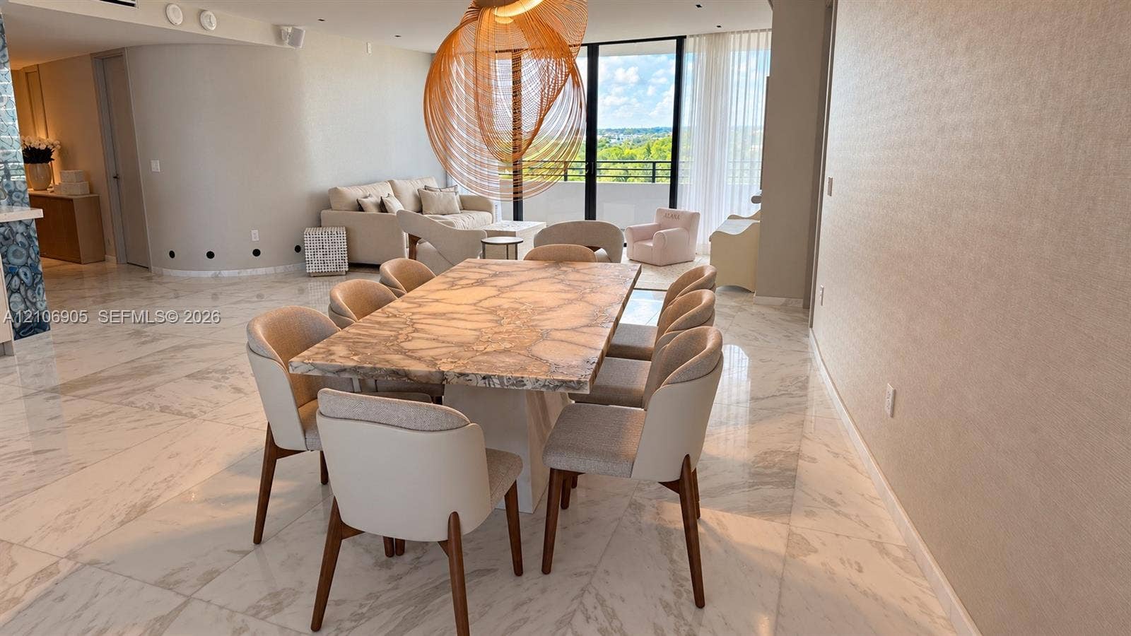720 NE 69th Street, #10N, Miami, FL 33138 Polished stone flooring, floor-to-ceiling windows, curved architectural wall, and modern hanging light fixture