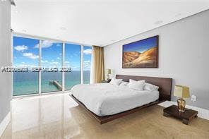 Floor-to-ceiling glass panel walls, light-toned stone flooring, and recessed ceiling lighting