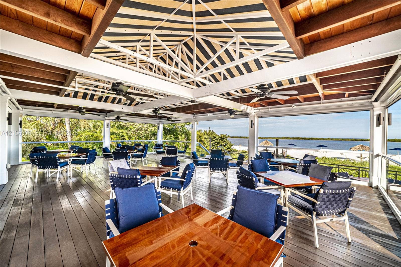 331 Wild Orchid Lane, Marco Island, Marco Island, FL 34145 Covered outdoor terrace featuring a wood-plank deck, exposed timber-beam ceiling, overhead fans, and a waterfront backdrop