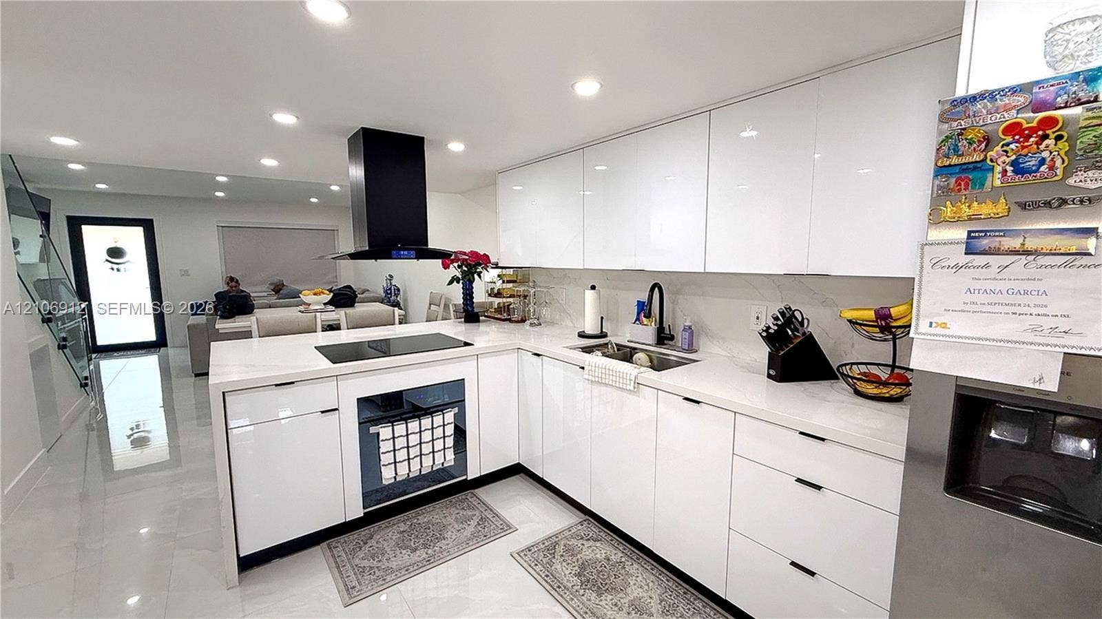 1142 W 42nd Street, #19, Hialeah, FL 33012 Kitchen featuring high-gloss cabinetry, stone countertops, a large island with an integrated cooktop, a contemporary black chimney-style range hood, and recessed lighting