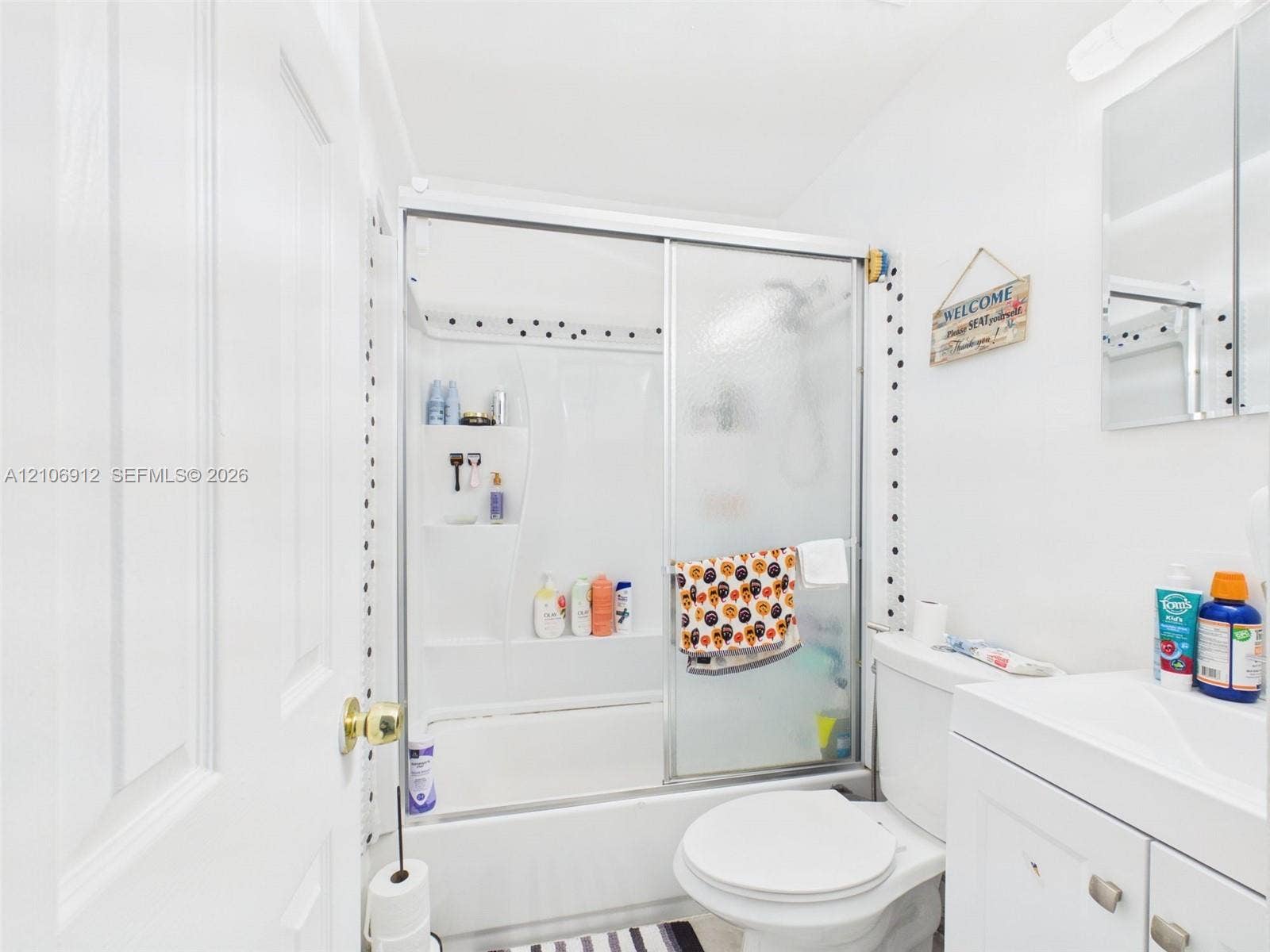 1142 W 42nd Street, #19, Hialeah, FL 33012 Bathroom featuring a shower and tub combination with sliding glass doors, a white vanity cabinet, and a mirrored medicine cabinet