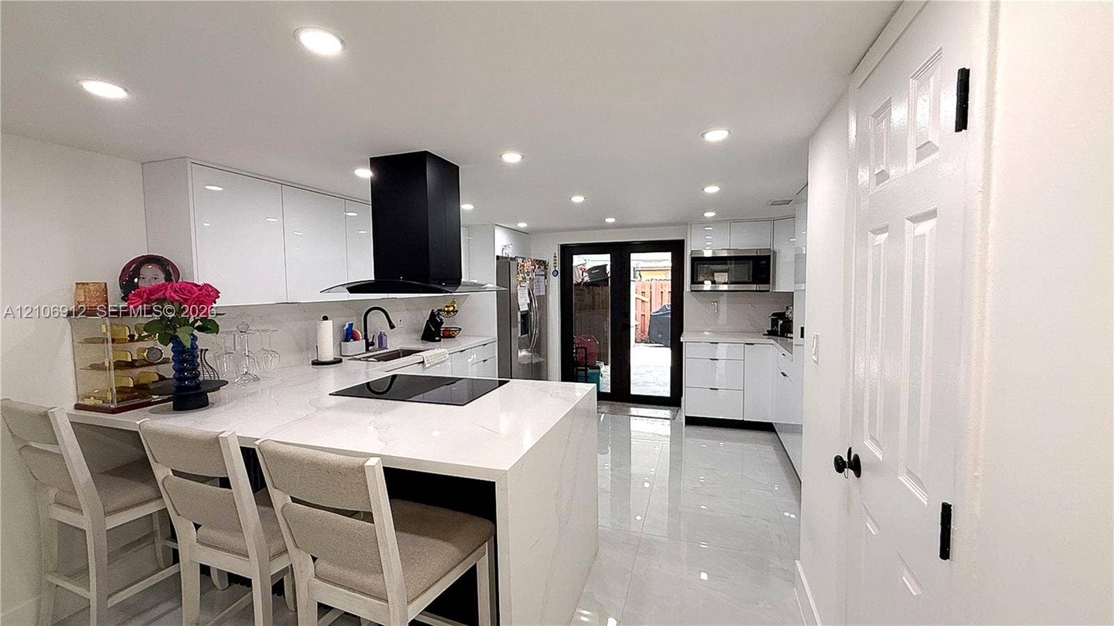 1142 W 42nd Street, #19, Hialeah, FL 33012 Kitchen featuring high-gloss white cabinetry, a waterfall-edge countertop, black range hood, polished tile flooring, and integrated recessed lighting