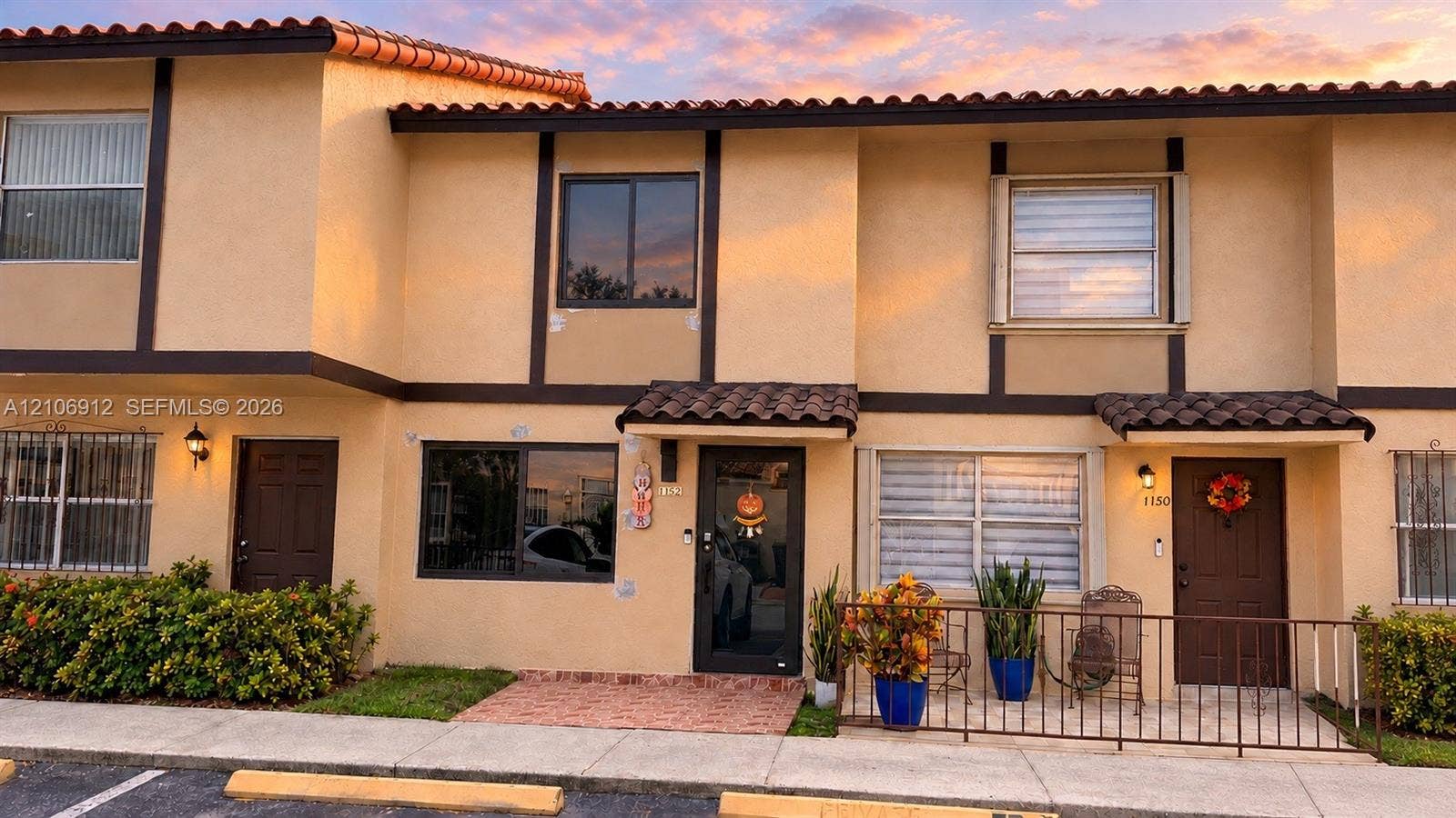 1142 W 42nd Street, #19, Hialeah, FL 33012 Two-story stucco exterior featuring a tiled roof, dark-framed windows, brick-paved entryway, and metal exterior railings