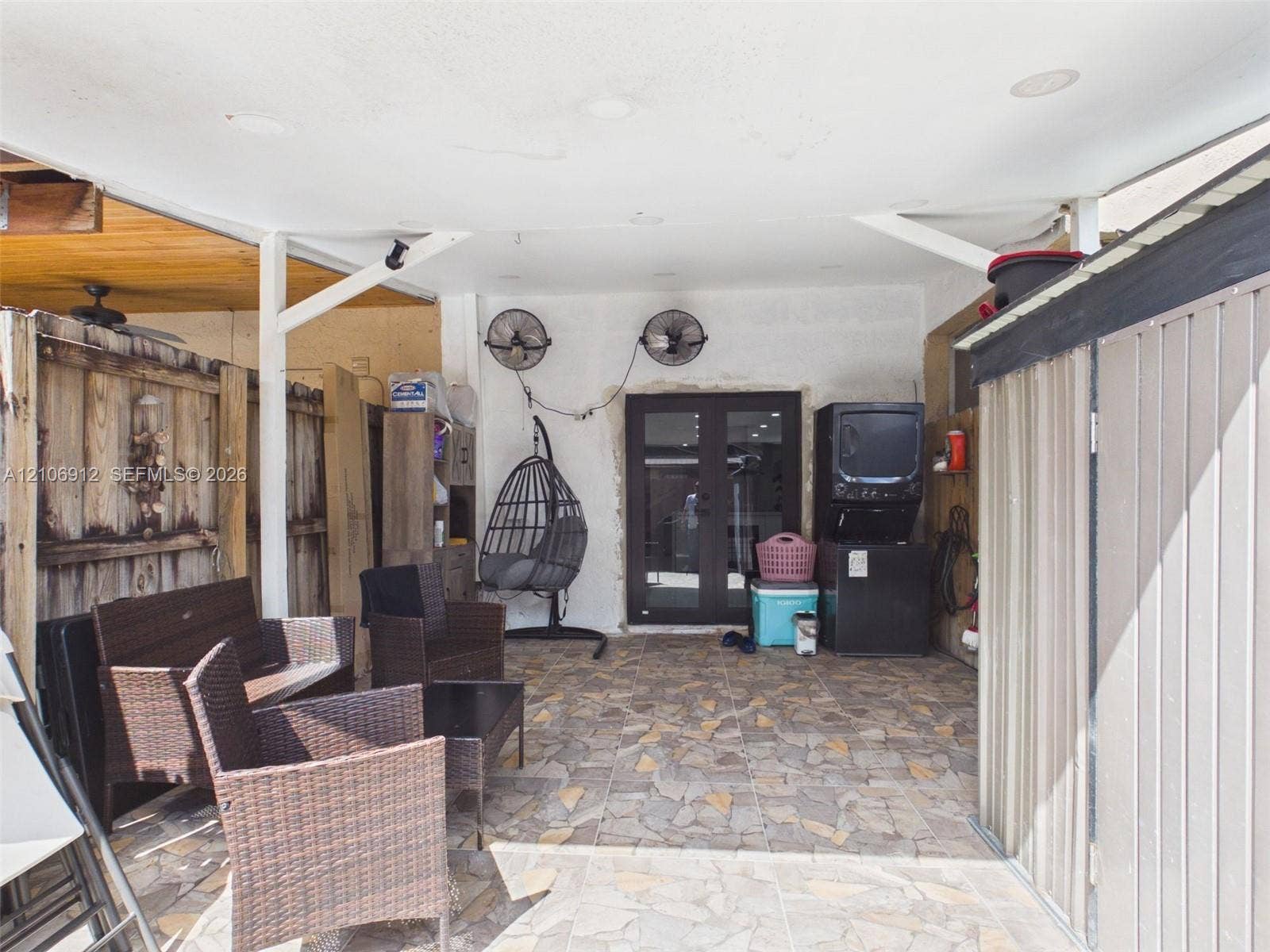 1142 W 42nd Street, #19, Hialeah, FL 33012 Covered patio featuring stone-tiled flooring, wall-mounted industrial fans, and a double-door entry