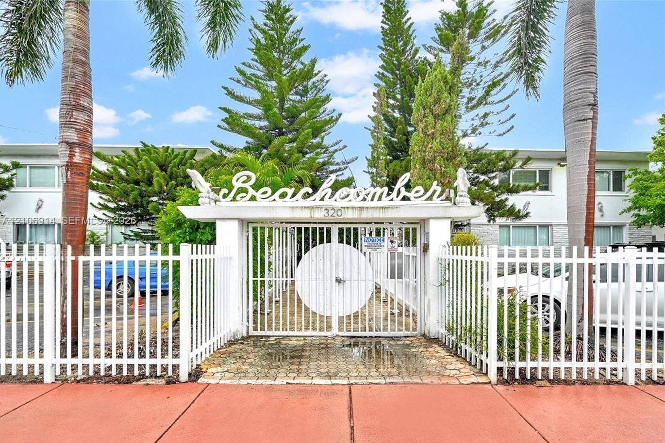 320 85th Street, #20, Miami Beach, Miami Beach, FL 33141 Gated entrance featuring white decorative metal fencing, stone-paver walkway, and mature palms