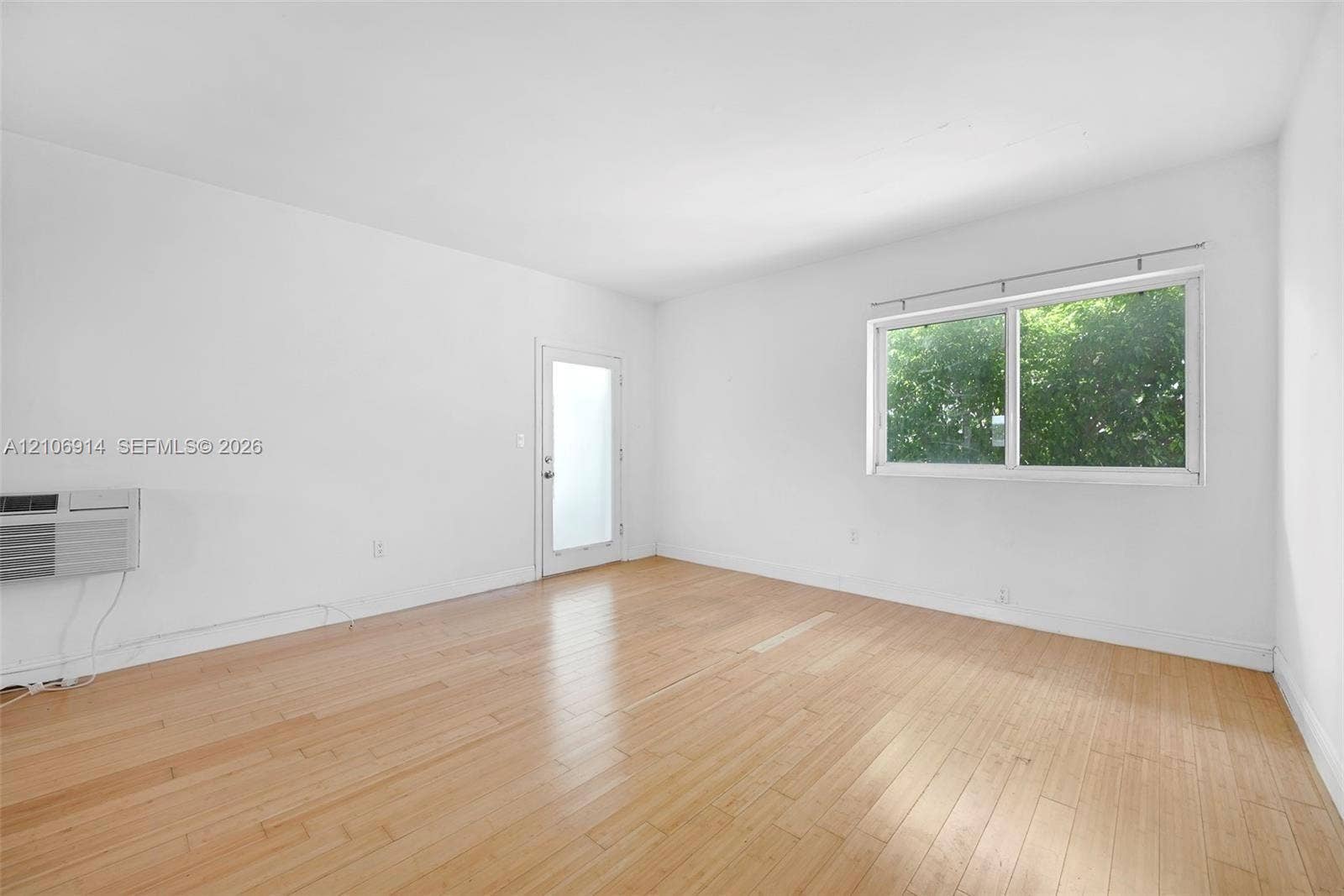 320 85th Street, #20, Miami Beach, Miami Beach, FL 33141 Room featuring wood-finish flooring, a single-pane horizontal sliding window, and a glass-panel exterior door